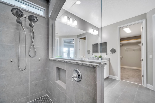 bathroom featuring tile patterned flooring, vanity, a healthy amount of sunlight, and a tile shower