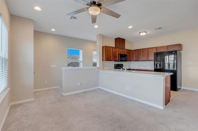 kitchen featuring light carpet, kitchen peninsula, a healthy amount of sunlight, and black appliances