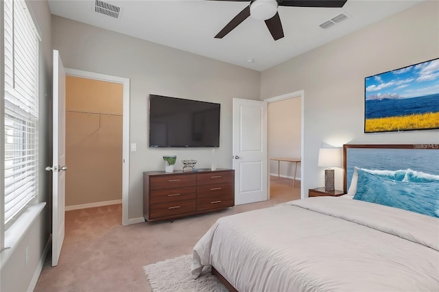 carpeted bedroom with a walk in closet, a closet, and ceiling fan