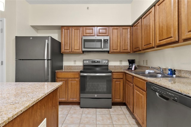 kitchen with light stone countertops, light tile patterned floors, stainless steel appliances, and sink