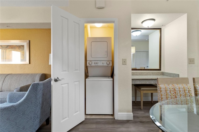 clothes washing area with dark wood-type flooring and stacked washer and clothes dryer