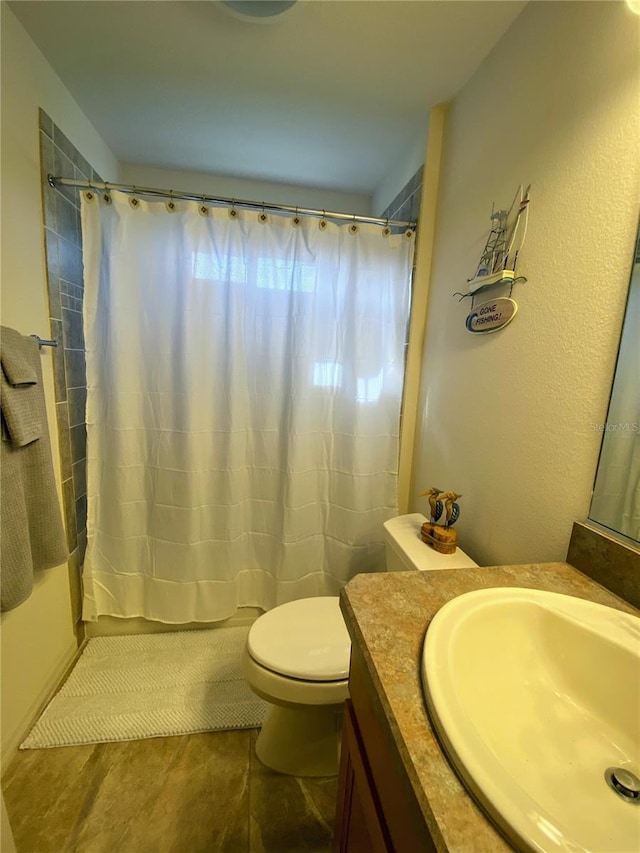 bathroom with tile patterned floors, walk in shower, vanity, and toilet