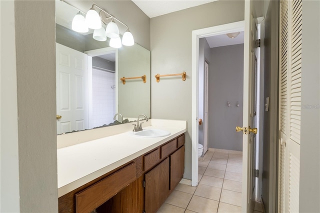 bathroom with toilet, vanity, and tile patterned floors