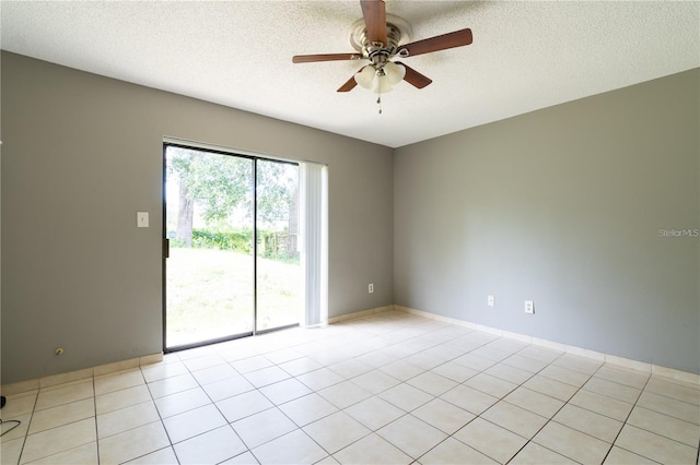 spare room featuring ceiling fan, light tile patterned floors, and a textured ceiling