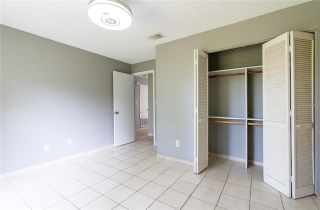 unfurnished bedroom with light tile patterned floors, a textured ceiling, and a closet