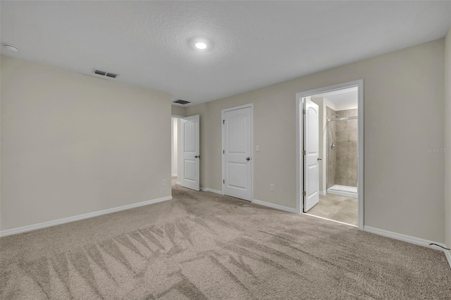 unfurnished bedroom featuring connected bathroom, a closet, light colored carpet, and a textured ceiling