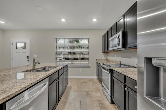 kitchen with light stone counters, sink, and appliances with stainless steel finishes