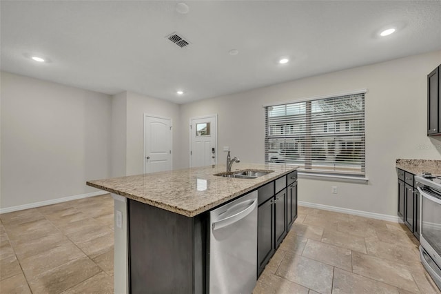 kitchen featuring light stone countertops, appliances with stainless steel finishes, a kitchen island with sink, and sink