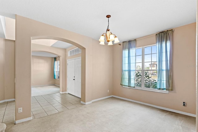 carpeted empty room with a chandelier