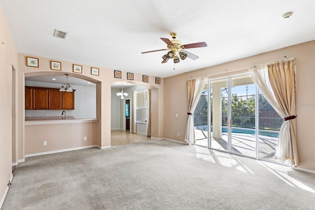 unfurnished living room with ceiling fan, sink, light carpet, and a textured ceiling