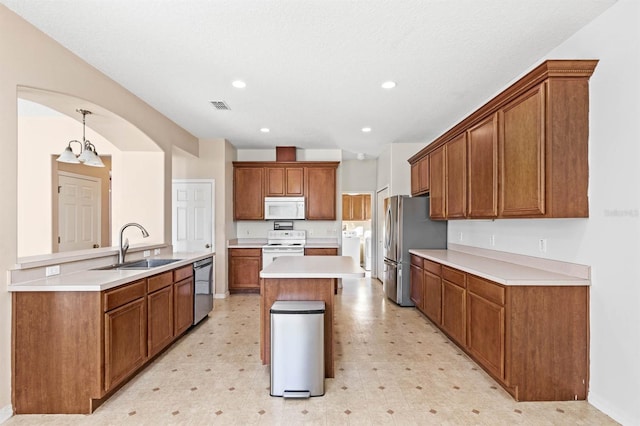 kitchen with kitchen peninsula, stainless steel appliances, washer and clothes dryer, sink, and pendant lighting