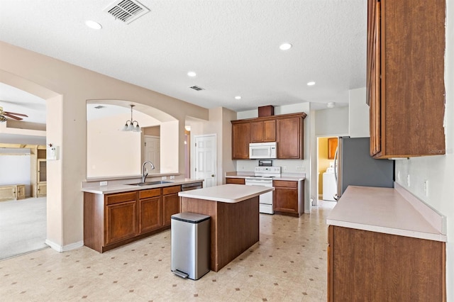 kitchen with white appliances, sink, ceiling fan, decorative light fixtures, and a kitchen island