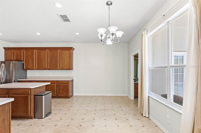 kitchen featuring pendant lighting, a kitchen island, stainless steel refrigerator, and a notable chandelier