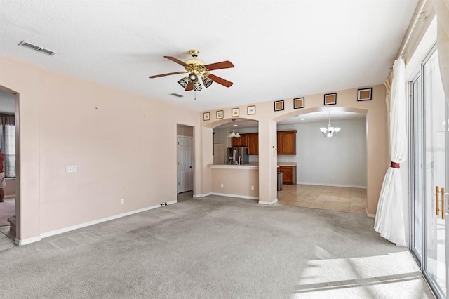 unfurnished living room featuring light carpet and ceiling fan with notable chandelier