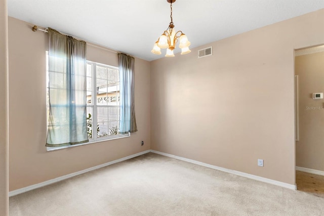 empty room with a notable chandelier and light carpet