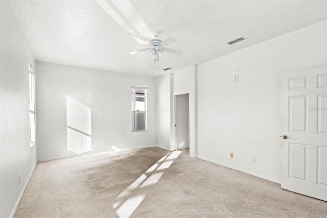 spare room featuring a textured ceiling, ceiling fan, and light carpet