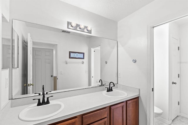 bathroom featuring vanity, toilet, and a textured ceiling