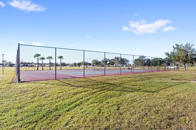 view of tennis court with a yard