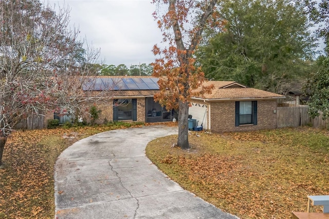 single story home with a garage and solar panels