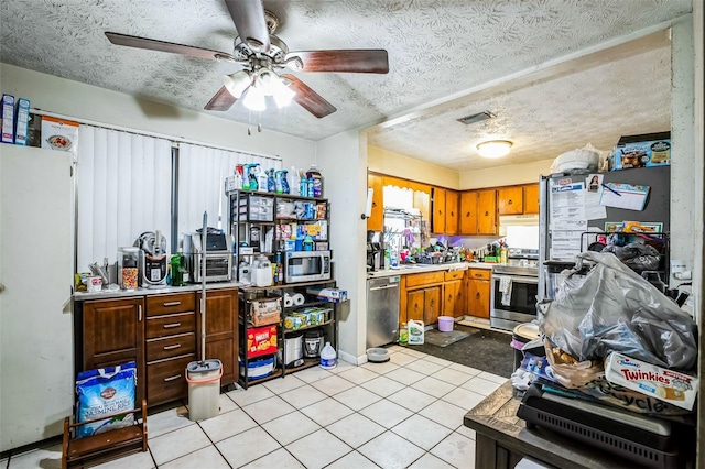 kitchen with ceiling fan, light tile patterned floors, a textured ceiling, and appliances with stainless steel finishes