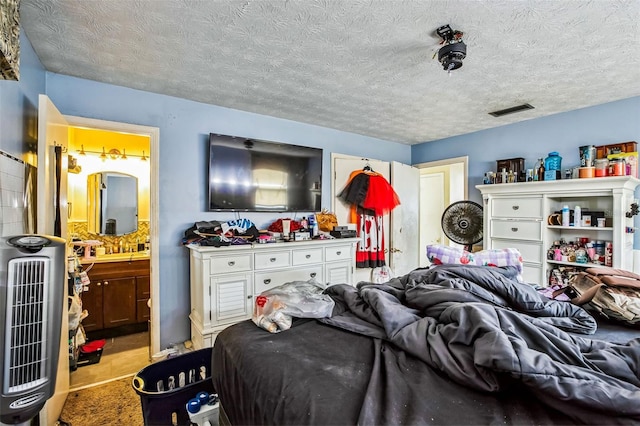 bedroom featuring heating unit, a textured ceiling, and ensuite bath