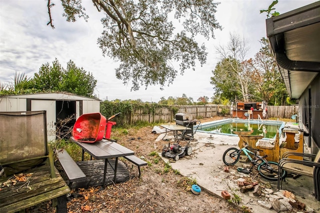 view of yard with a fenced in pool and a storage unit