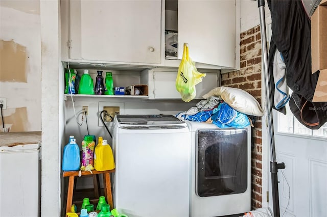 laundry area with independent washer and dryer, cabinets, and brick wall