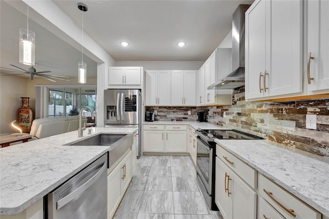 kitchen featuring appliances with stainless steel finishes, ceiling fan, sink, wall chimney range hood, and white cabinetry