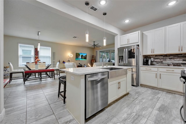 kitchen with decorative backsplash, appliances with stainless steel finishes, white cabinetry, and hanging light fixtures