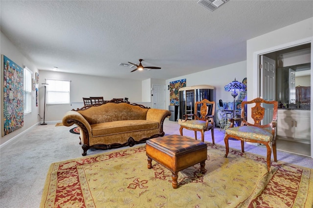 living room featuring ceiling fan, light colored carpet, and a textured ceiling