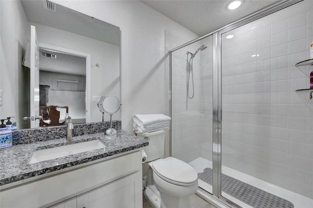 bathroom featuring vanity, toilet, a shower with shower door, and a textured ceiling