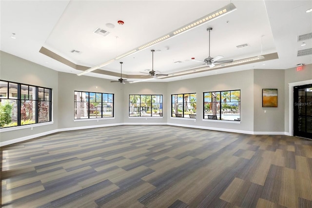 unfurnished living room featuring dark colored carpet and a raised ceiling