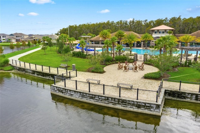 view of property's community featuring a water view, a pool, and a lawn