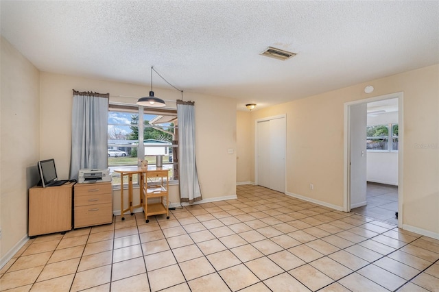 office area with a healthy amount of sunlight, light tile patterned floors, and a textured ceiling