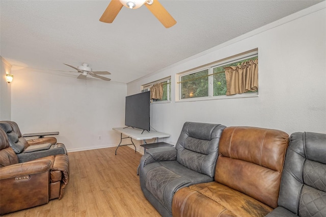 living room with a textured ceiling, light hardwood / wood-style flooring, and ceiling fan