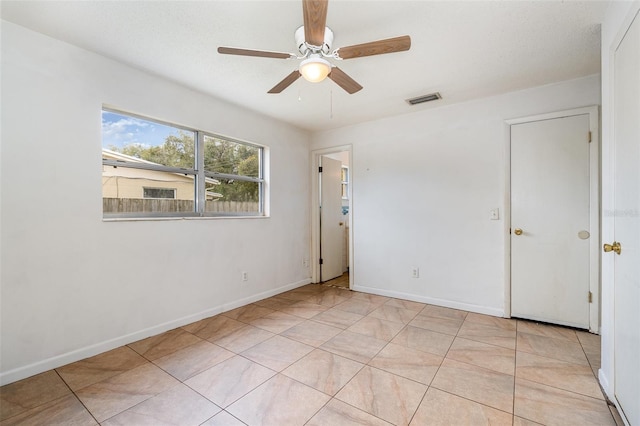 empty room with ceiling fan and light tile patterned floors