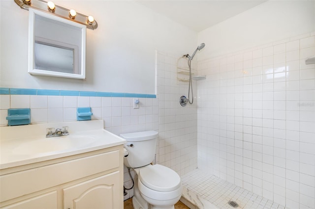 bathroom featuring a tile shower, vanity, toilet, and tile walls