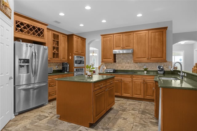 kitchen featuring a center island, sink, dark stone countertops, tasteful backsplash, and stainless steel fridge with ice dispenser