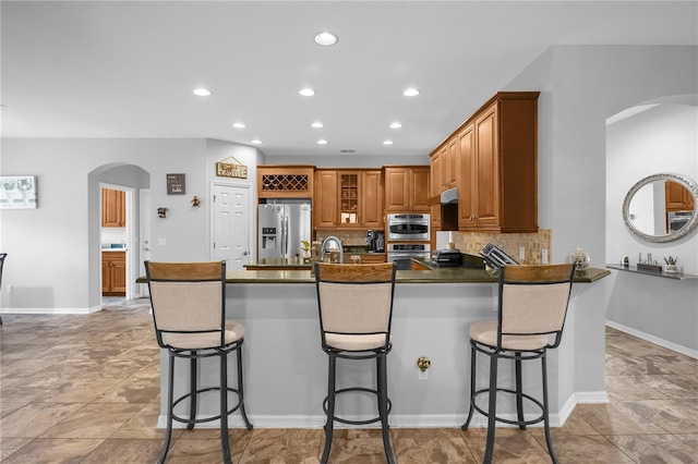 kitchen with a kitchen bar, tasteful backsplash, stainless steel appliances, and sink