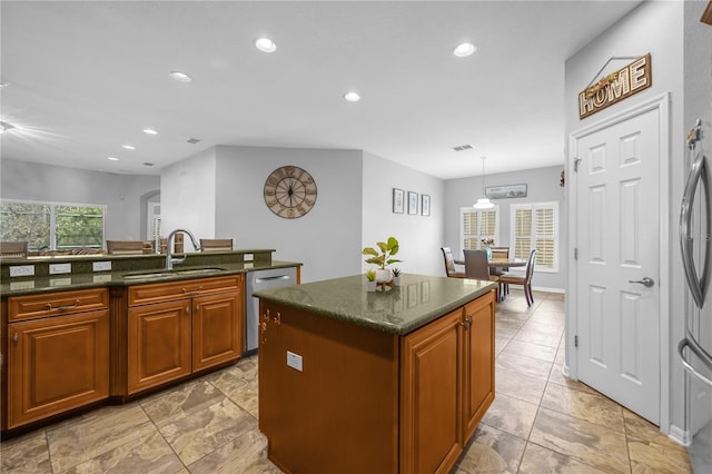 kitchen featuring stainless steel dishwasher, a wealth of natural light, sink, pendant lighting, and a center island