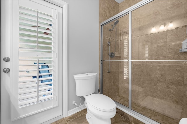 bathroom with tile patterned floors, toilet, and an enclosed shower