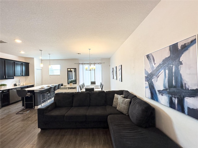 living room with a textured ceiling, an inviting chandelier, and dark hardwood / wood-style flooring