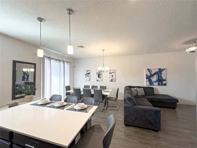 dining space with dark wood-type flooring, a textured ceiling, and a notable chandelier