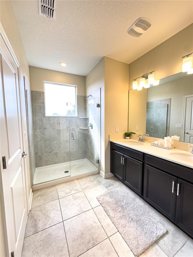 bathroom with an enclosed shower, vanity, tile patterned floors, and a textured ceiling