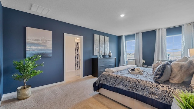 carpeted bedroom featuring a textured ceiling and ensuite bathroom