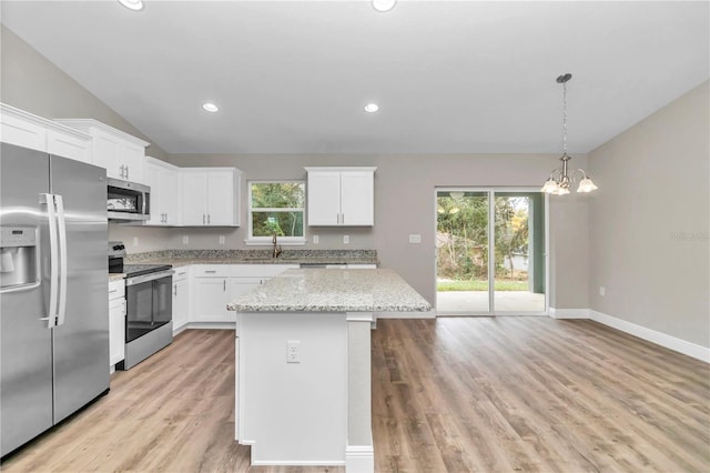 kitchen with light stone countertops, appliances with stainless steel finishes, sink, white cabinets, and a center island