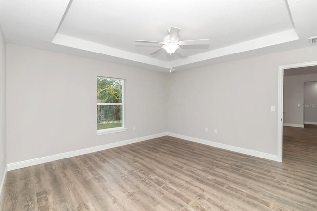 spare room with a raised ceiling, ceiling fan, and hardwood / wood-style flooring