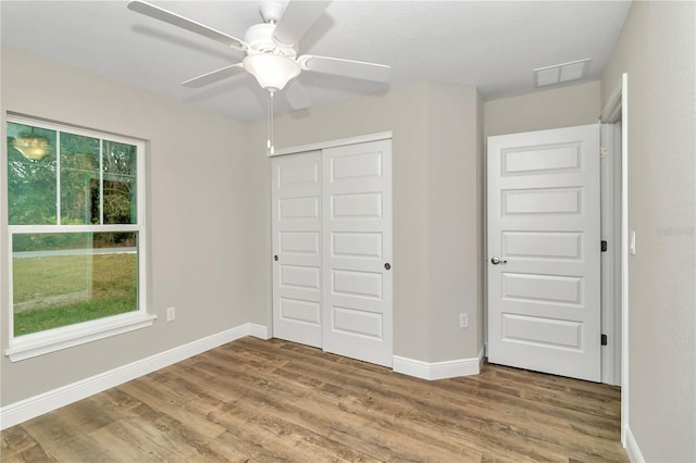 unfurnished bedroom featuring ceiling fan, a closet, and wood-type flooring