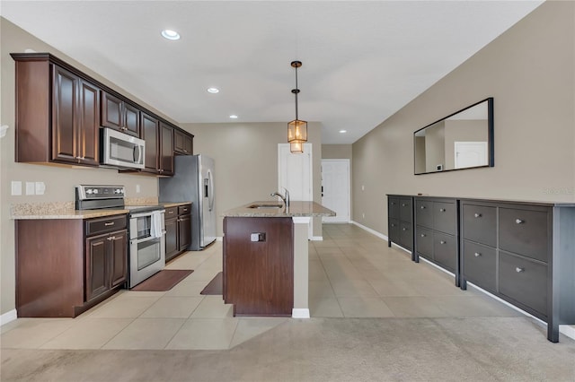 kitchen featuring pendant lighting, stainless steel appliances, dark brown cabinets, and a center island with sink