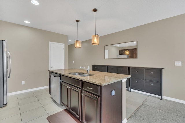 kitchen with dark brown cabinetry, light stone countertops, sink, a kitchen island with sink, and appliances with stainless steel finishes